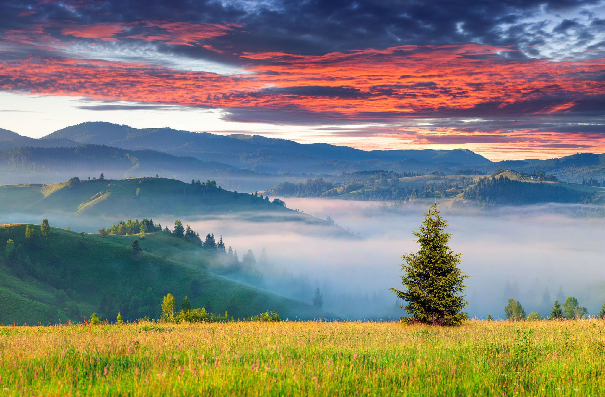 Mountain landscape with colorful sunset sky and foggy hills